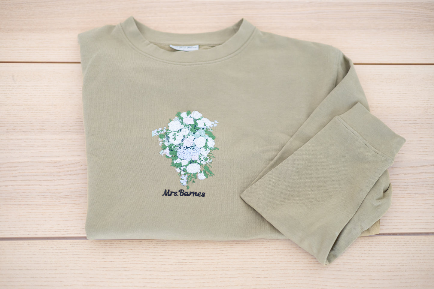 Embroidered wedding bouquet crewneck laid flat showing full design with custom name