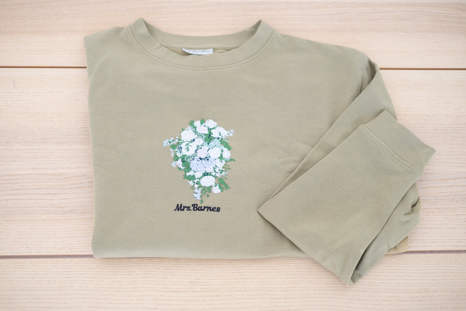 Embroidered wedding bouquet crewneck laid flat showing full design with custom name