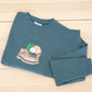 Custom embroidered crewneck in forest green laid flat showing floral boot design